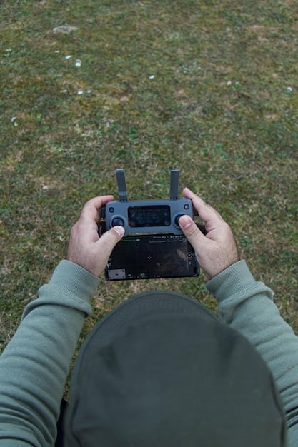 A close-up of a drone operator using a remote control, focusing on their hand movements and the drone's display screen. The setting should be an outdoor environment with a clear sky in the background.