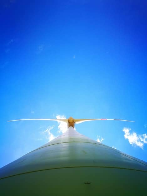 Close-up of an aircraft wing with aerodynamic modifications for improved fuel efficiency, set against a bright blue sky, showing the details of green technology.