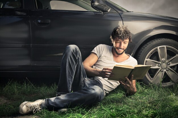 A driver in a Level 3 autonomous car reading a book while the car is driving on the highway. The image should convey a sense of relaxation and productivity.