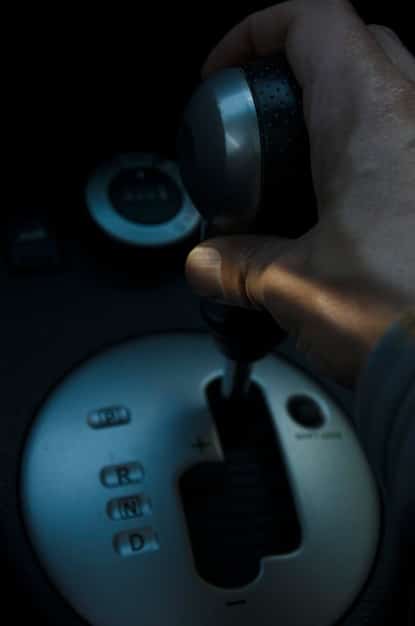 A detailed view of an infrared sensor mounted on the steering wheel column of a car. The sensor is actively emitting infrared light, illustrating its role in tracking hand gestures within the vehicle's cabin. The image highlights the technological aspect of the sensor and its integration into the car's interior.
