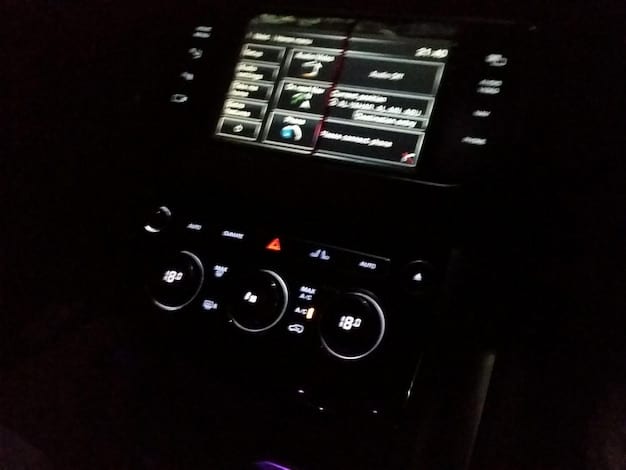 A close-up of a car's central console displaying a complex interface showcasing various software controls. The screen highlights features like autonomous driving modes, customized driving preferences, real-time data analytics, and integrated connected services.