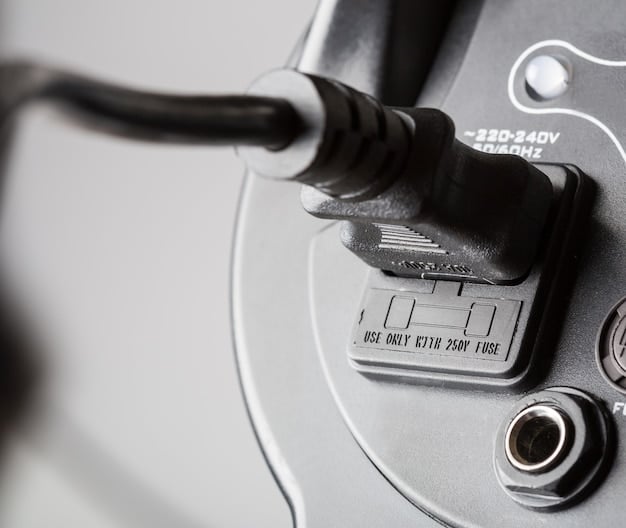 A close-up shot of a Tesla NACS connector plugged into a Tesla vehicle. The focus is on the connector itself, highlighting its compact size and sleek design. The Tesla logo is visible on the charging port door.