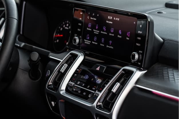 A wide interior shot of a modern car, focusing on the dashboard and infotainment screen. A driver’s hand hover over the center console, demonstrating a gesture to control the system, highlighting the car’s high-tech features and luxurious interior.
