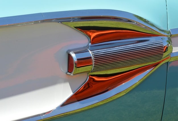 A rendering of a futuristic electric car with retro styling elements, such as a chrome grille, round headlights, and whitewall tires. The car is depicted in a futuristic cityscape, highlighting the blend of old and new.