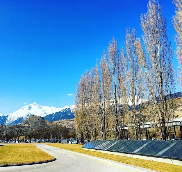 A panoramic view of a solar-powered charging station for electric vehicles in a scenic, natural setting. The charging station is surrounded by trees and mountains, emphasizing the connection between EVs and renewable energy.