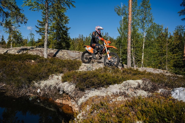 A 2024 KTM 390 Adventure navigating a rocky trail, showcasing its suspension travel and ground clearance. The rider is standing on the pegs, demonstrating proper off-road riding technique.