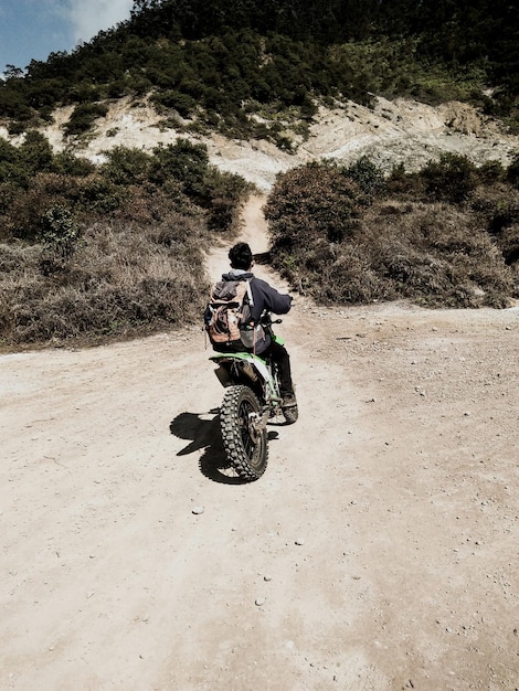 A rider on the 2024 BMW G 310 GS navigating a sandy trail. The rider is wearing full protective gear, including a helmet, riding jacket, and gloves. The bike's suspension is visibly absorbing the bumps, and the rider appears confident and in control.
